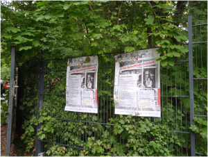 Dwa plakaty wiszące na ogrodzeniu